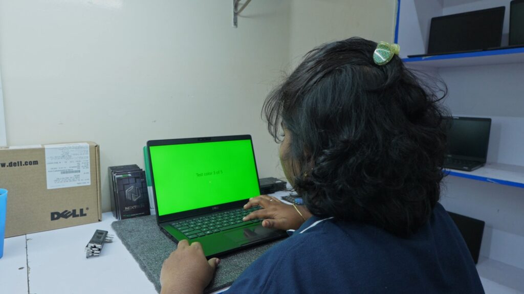 Bethel Computech technician testing and quality-checking a refurbished laptop before customer delivery.